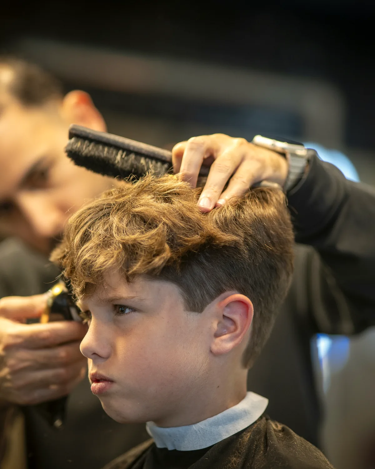 Barber van Estria werkt met kam en tondeuse aan een coupe
