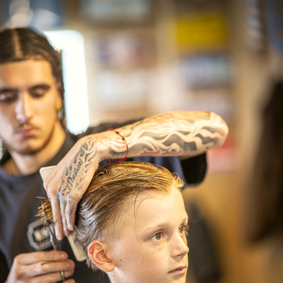 Barber van Estria knipt een klant, met kam en schaar in de hand